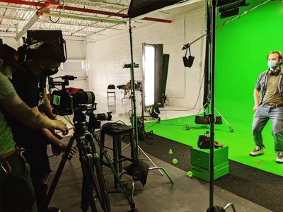 a picture of actor shooting in front of green screen with cameramen kino flo lights cameras sandbags softbox apple boxes stool