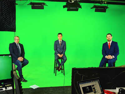 a picture of businessmen shooting in front of green screen with laptop recording lights sound blankets tv monitor stools